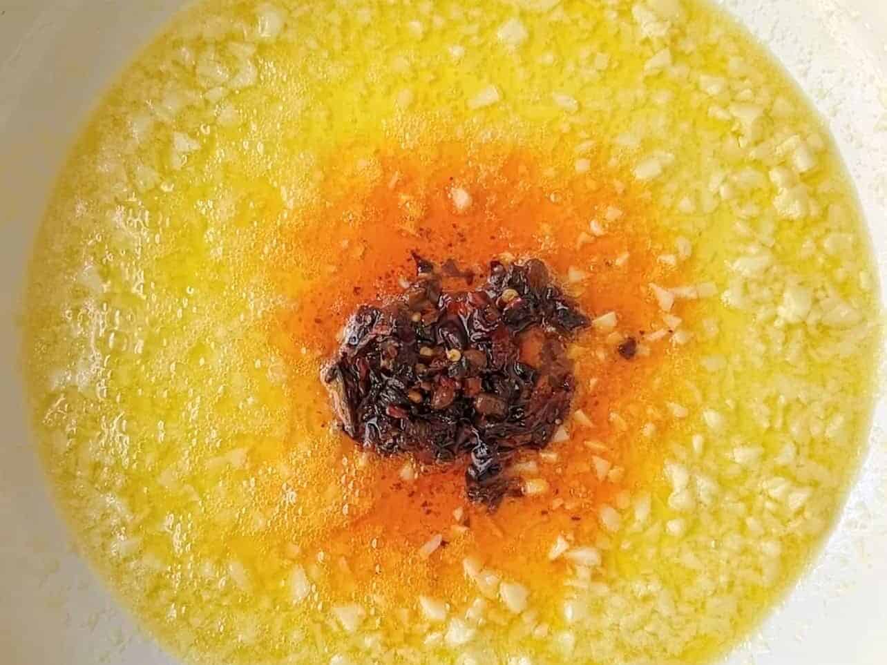 combining butter, garlic, and spicy chili crisp in a pan