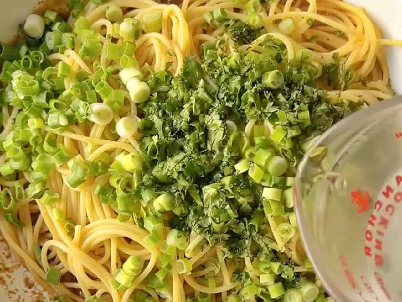 adding chopped cilantro, green onions, and pasta water