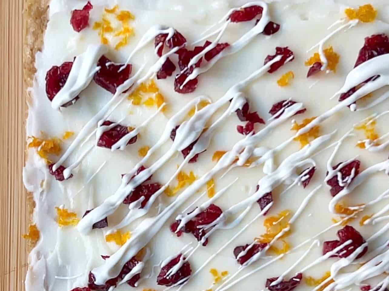 add cranberries, orange zest, white chocolate drizzle. chill before slicing
