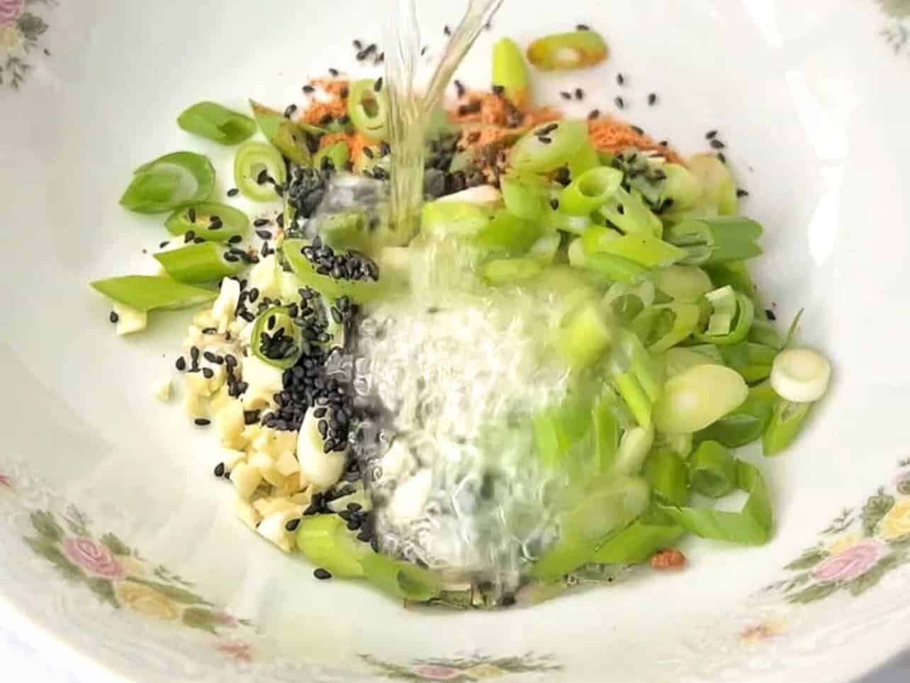 pour hot oil over aromatics to create garlic oil for shin ramyun hack