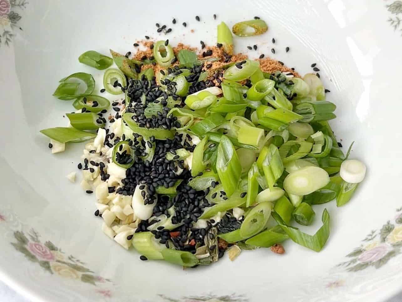 ramen seasoning, green onions, garlic, black sesame seeds in a bowl