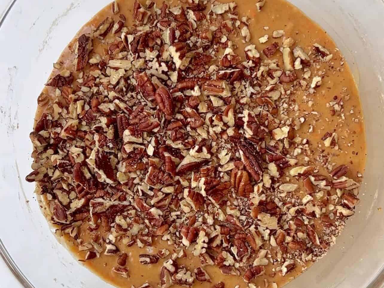 adding chopped pecans to carrot cake batter