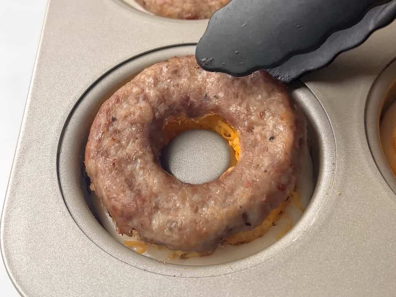 layer egg, cheese, and sausage in donut pan on top pancake batter