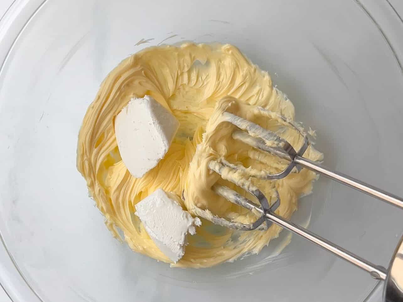 whip softened butter in a bowl, adding chunks of cold cream cheese