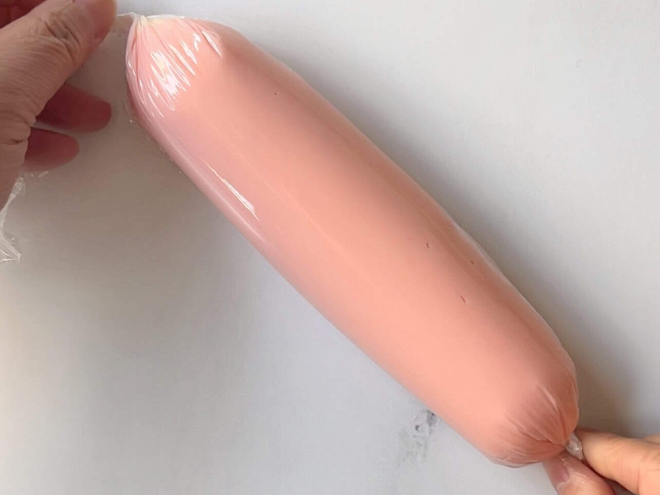 cling wrap in a cylinder holding pink frosting