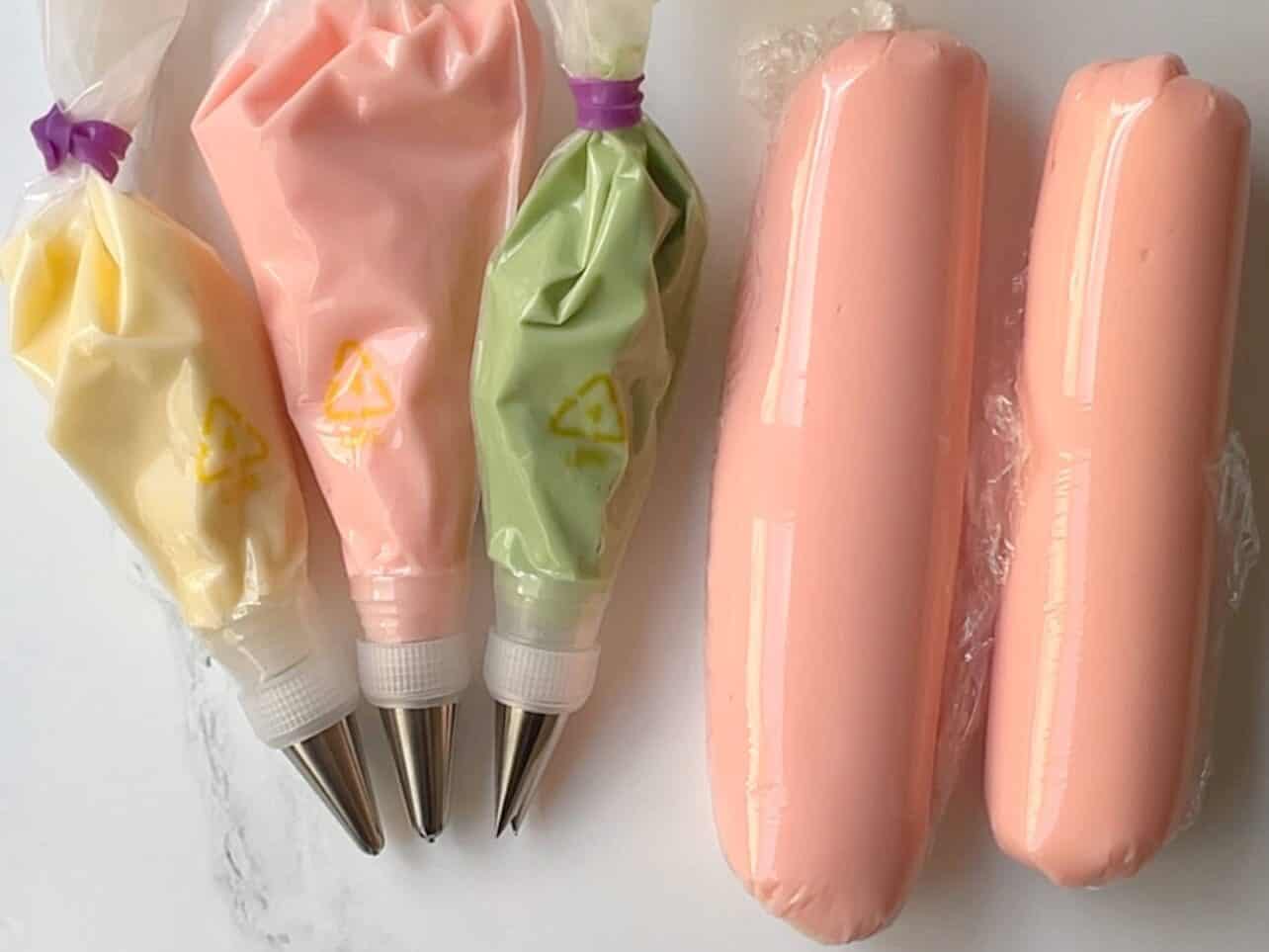 five piping bags filled with various colors of cream cheese frosting