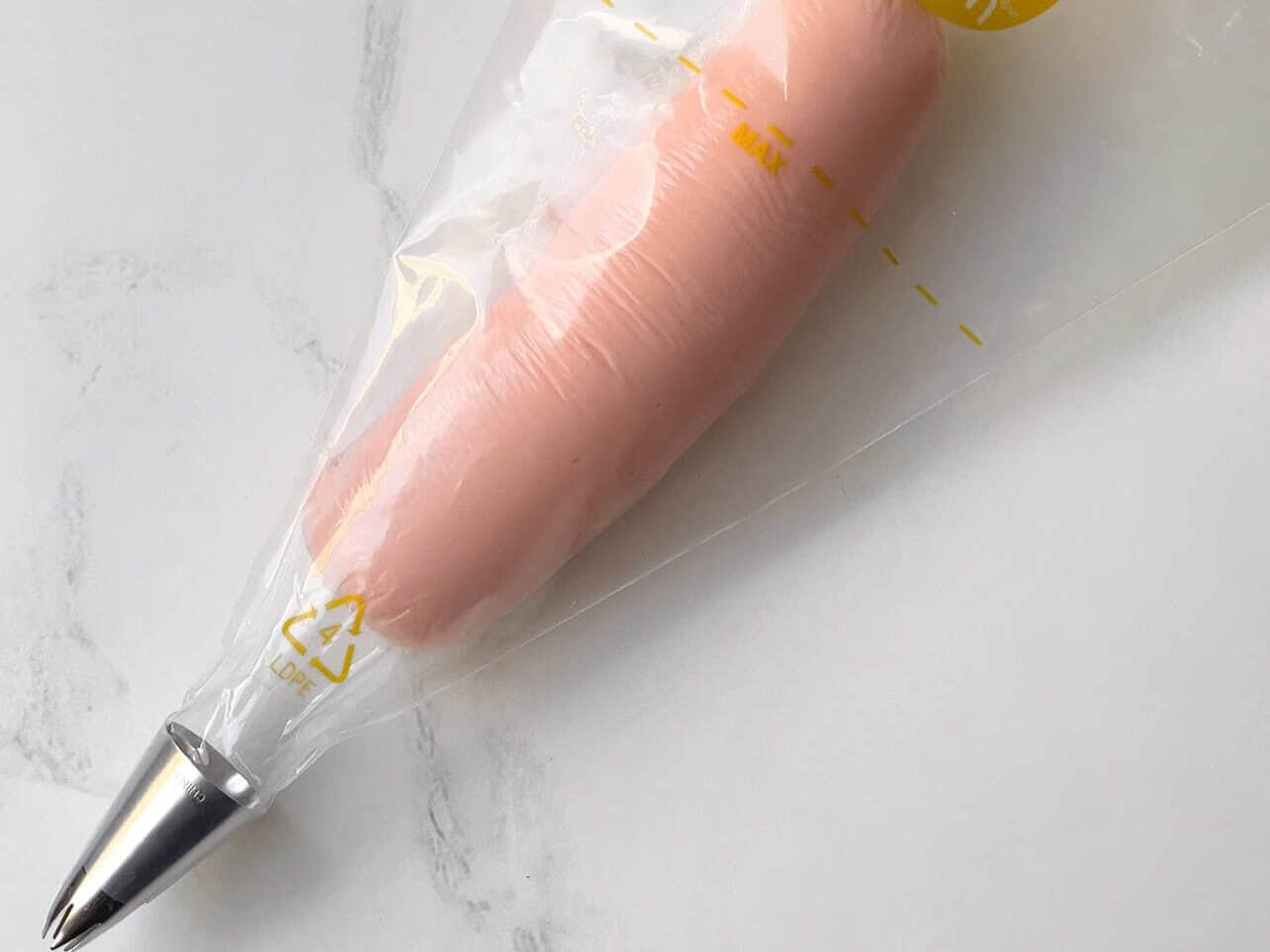 insert cling wrap filled frosting into empty piping bag