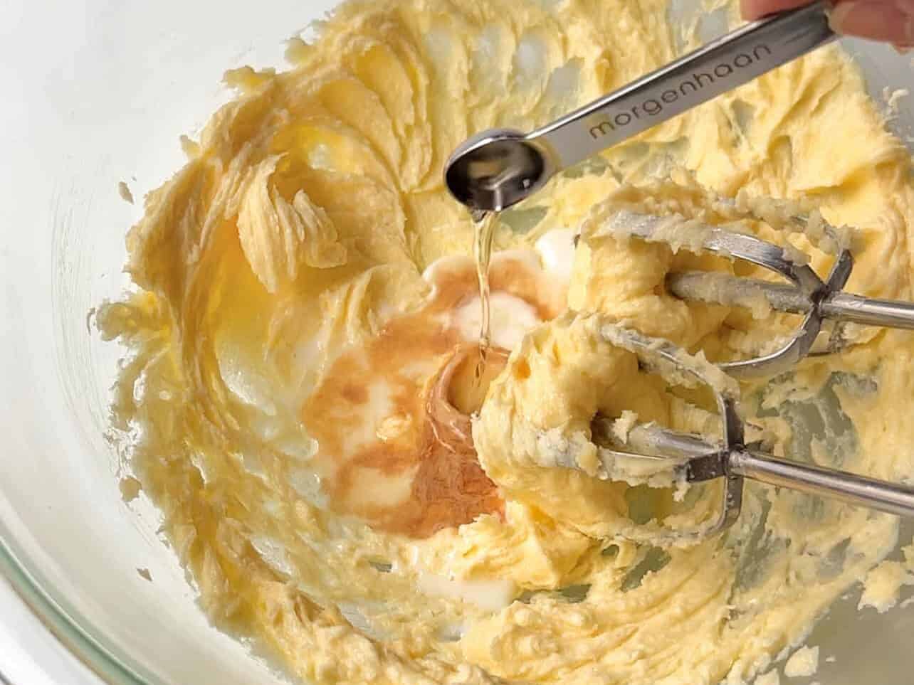 adding milk, vanilla, and almond extract to creamed butter