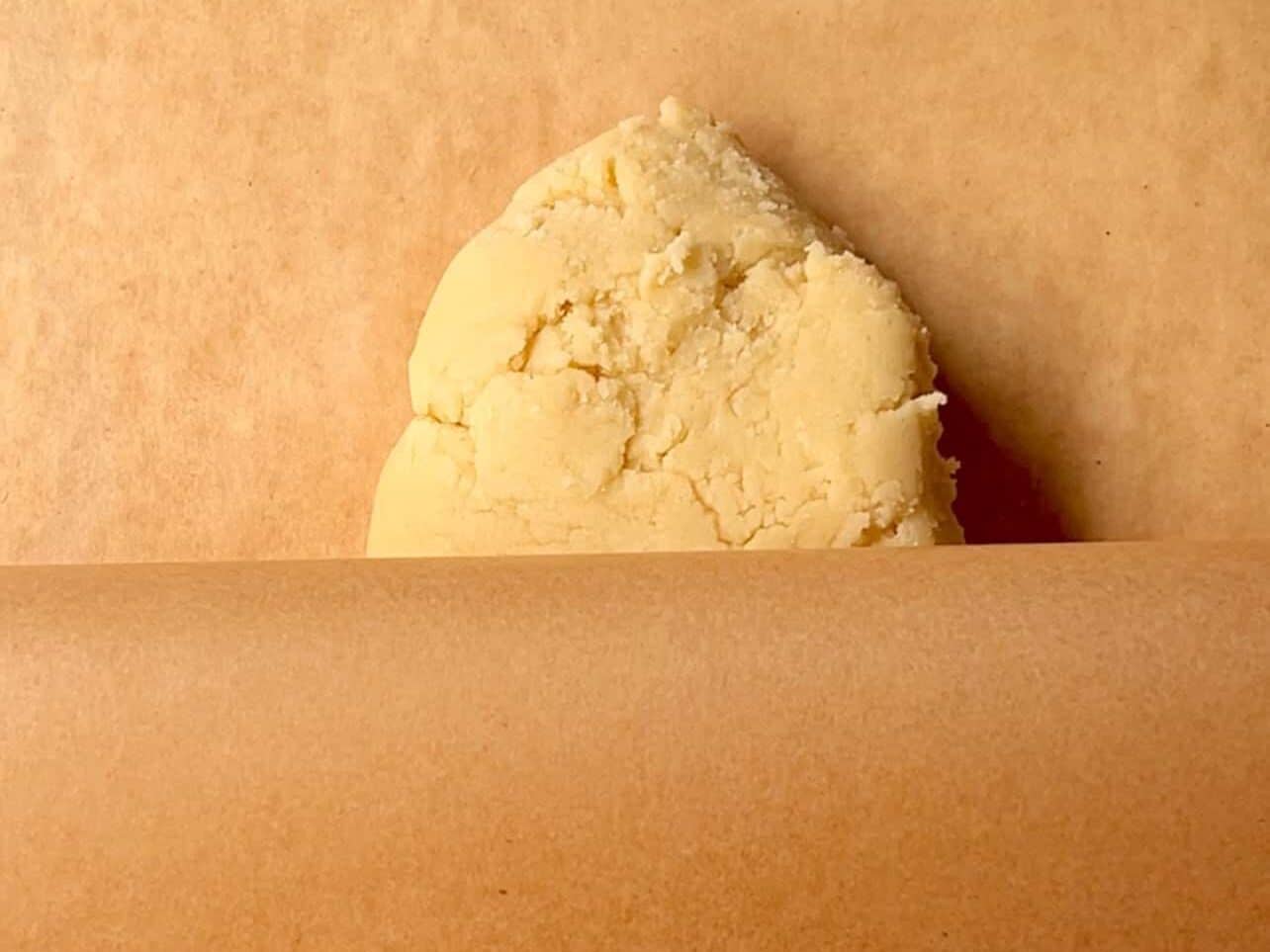 rolling cookie dough between two sheets of parchment paper