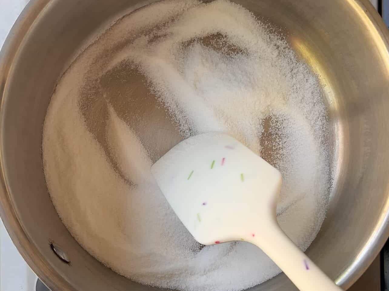 adding sugar to saucepan to start dry method of making homemade caramel
