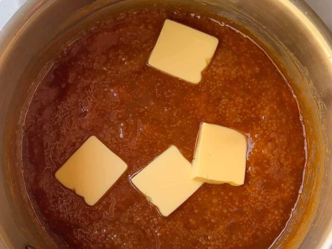 adding butter to homemade caramel sauce in saucepan