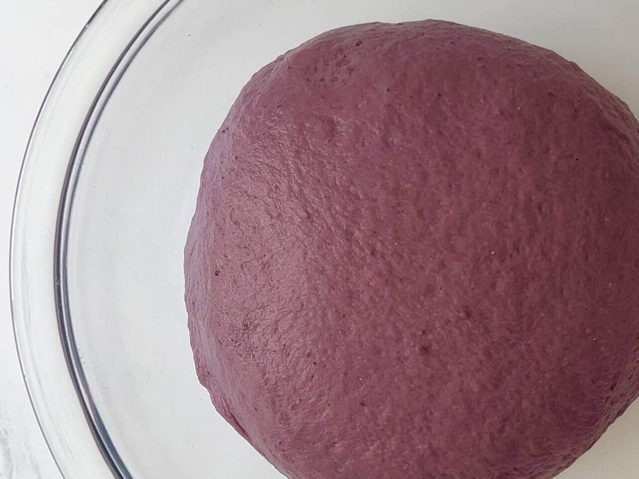 ube coconut dough rising in glass bowl