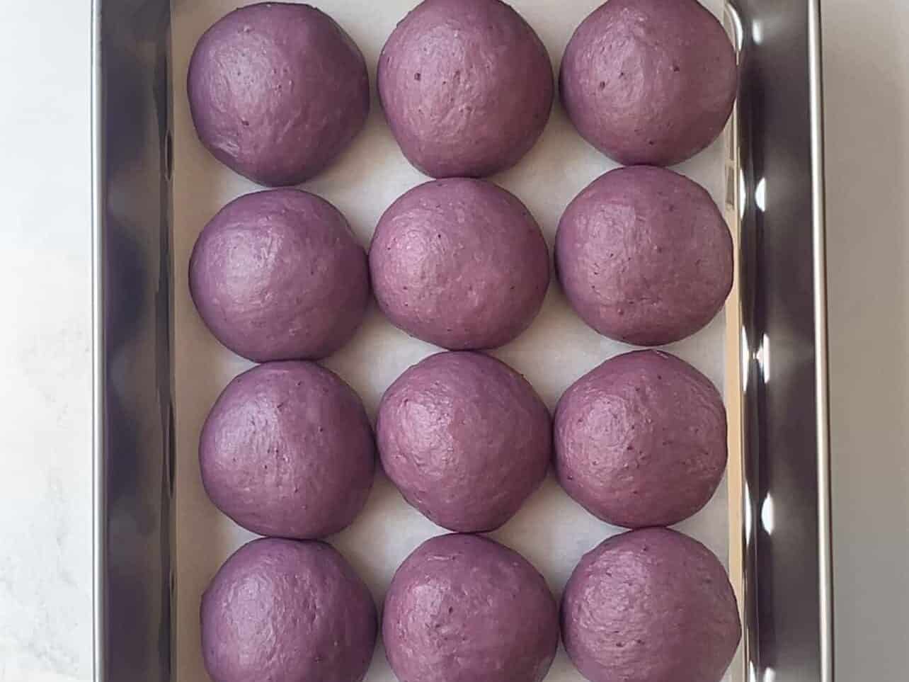 ube coconut dough proofing in a rectangle pan