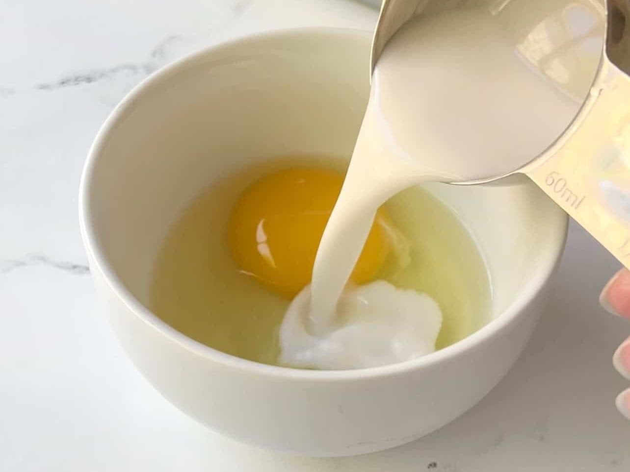 combining egg and coconut milk for egg wash to brush on ube coconut dough