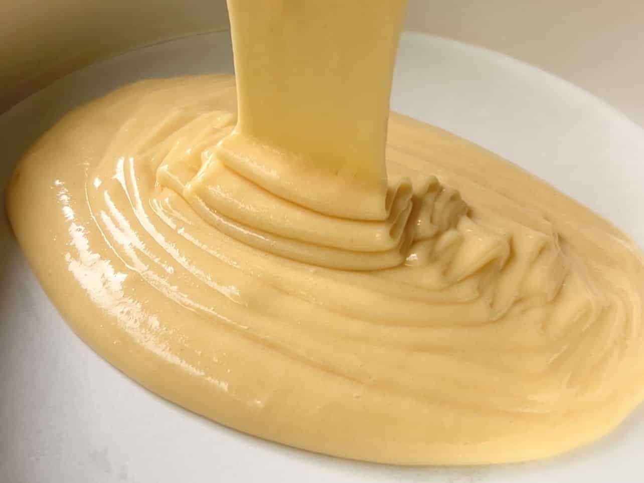 pouring vanilla cake batter into greased lined pan