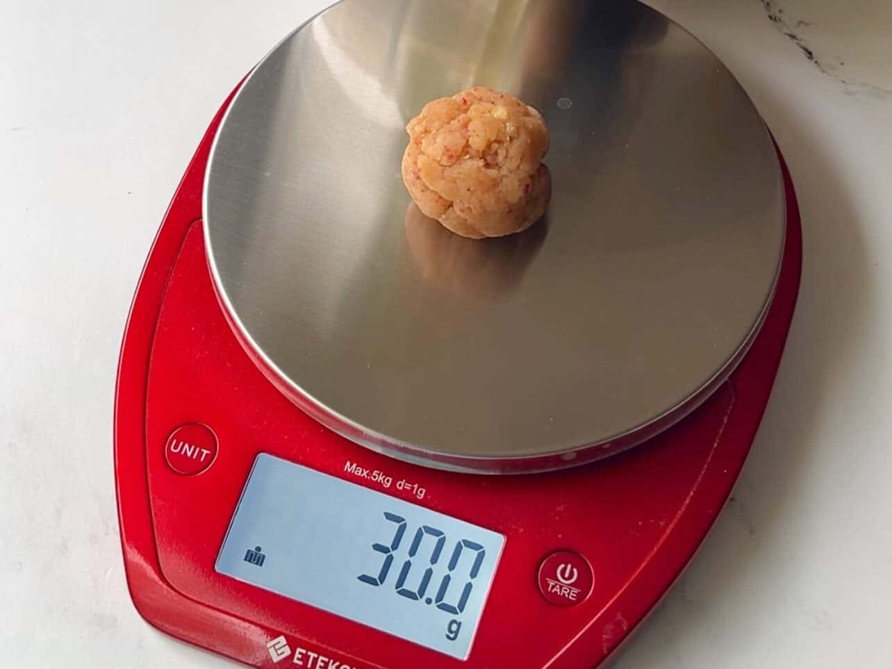 weighing each cake pop to ensure they are proper weight to stay attached to cake pop stick