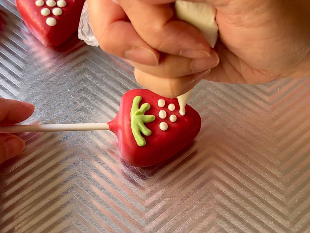 use white candy melts in piping bag to decorate seeds on Starbucks Copycat Strawberry And Cream Cake Pops