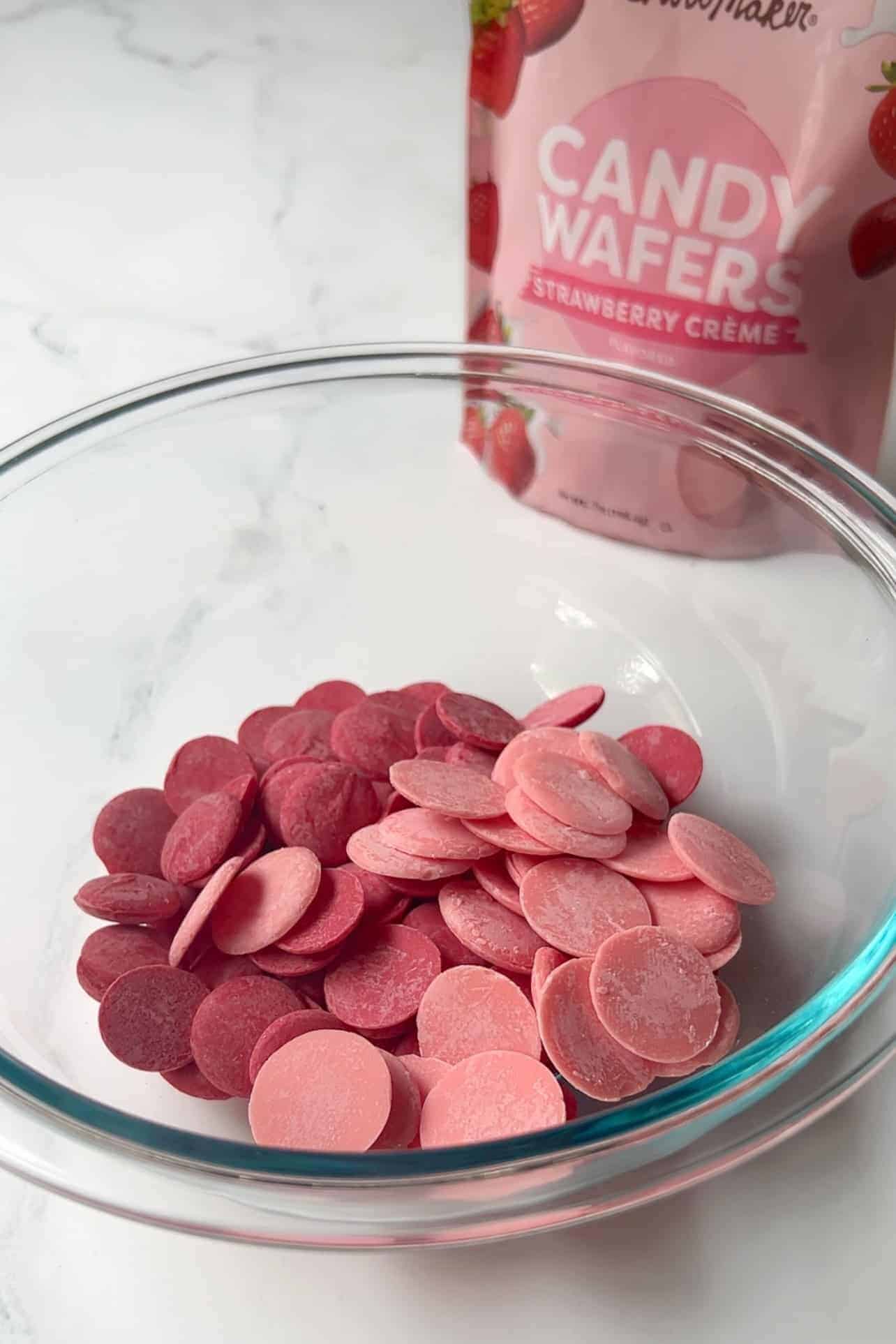 Strawberry crème candy wafers and red candy melts in a glass bowl 