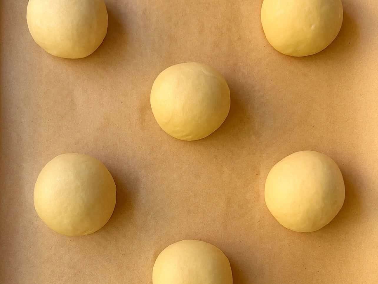 divided brioche dough balls on parchment paper/baking sheet ready for 2nd proof