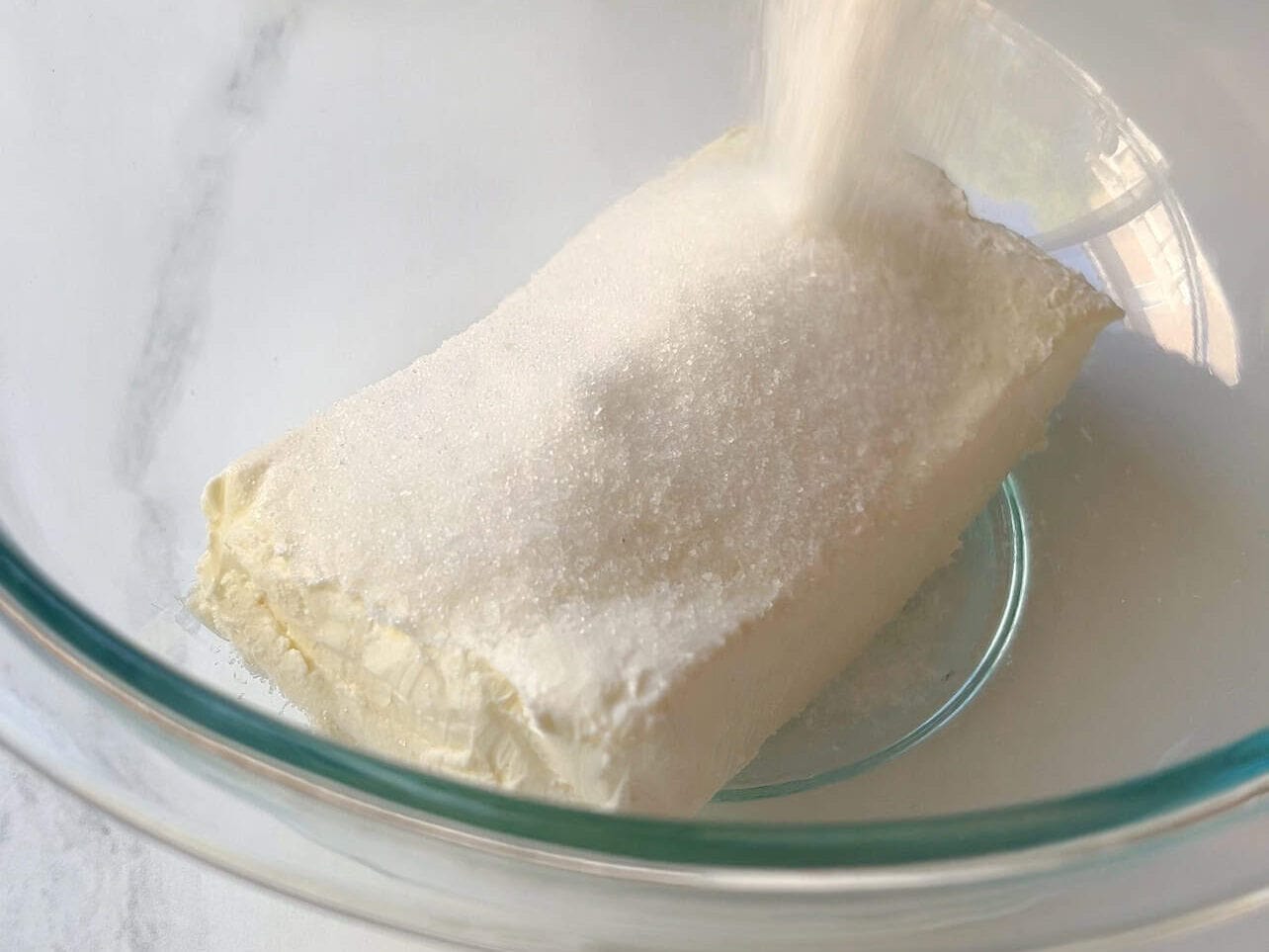 combining sugar with softened cream cheese to make cheese filling