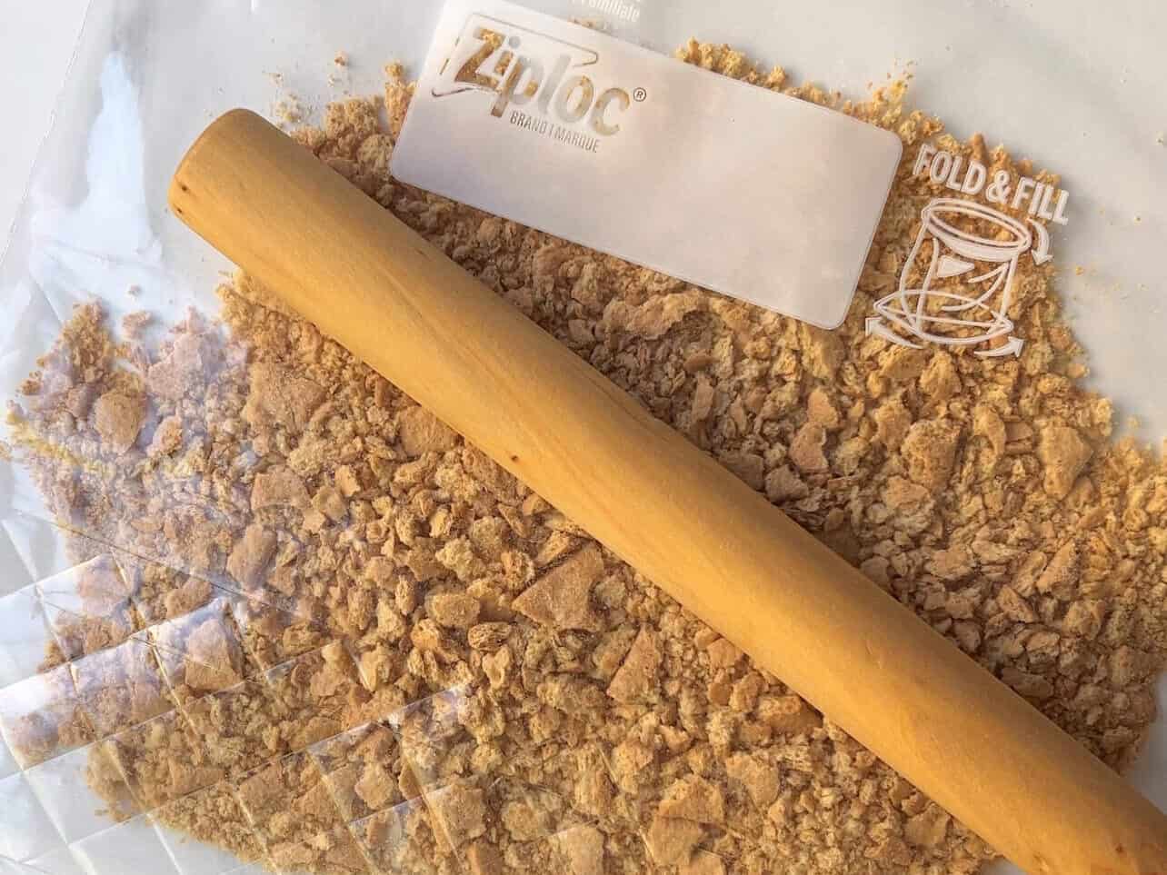 crushing graham crackers in a ziplock bag with a rolling pin