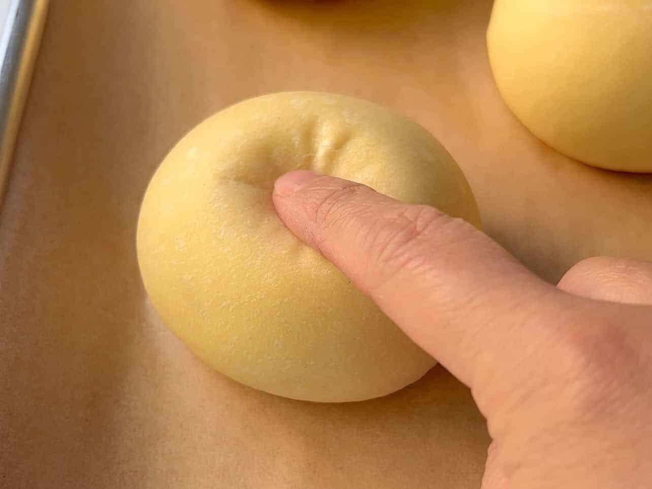 finger poke test to determine if brioche dough has been properly proofed and ready to bake.