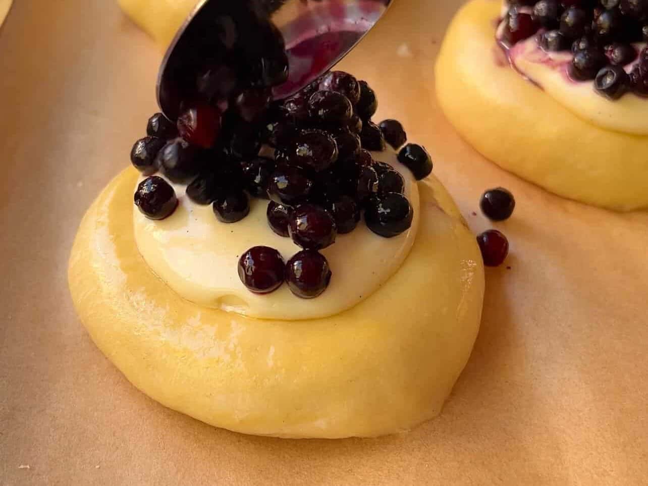 Spoon cheesecake filling and blueberries in center of brioche roll