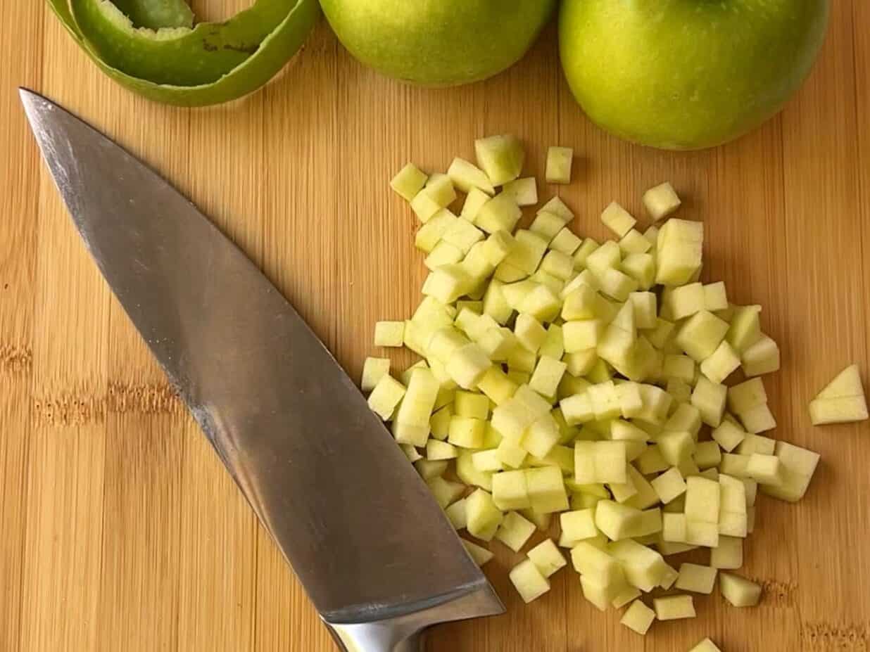 cutting board showing knife and chopped Granny Smith apples