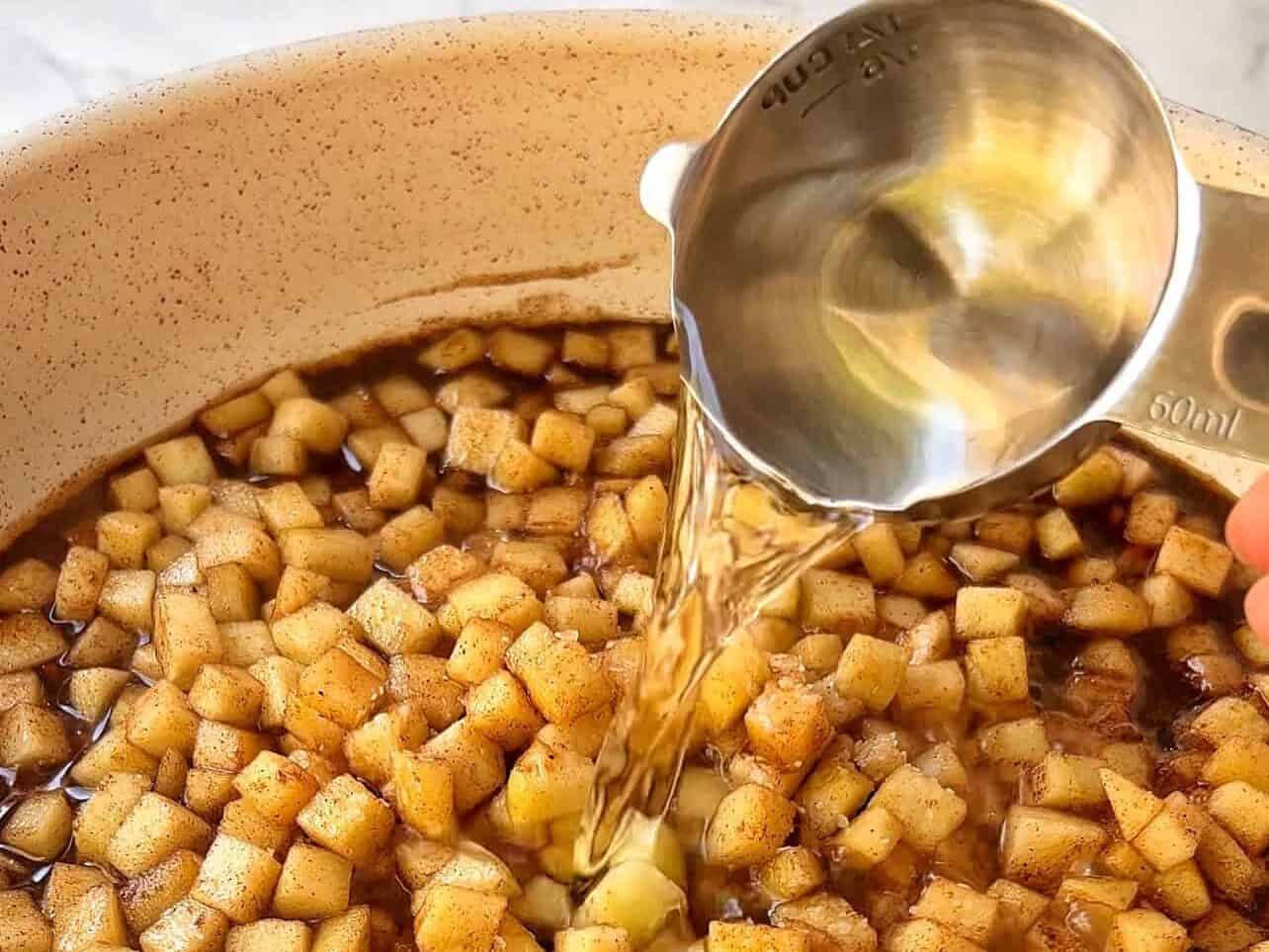 adding water and salt to simmer apple pie filling in large skillet