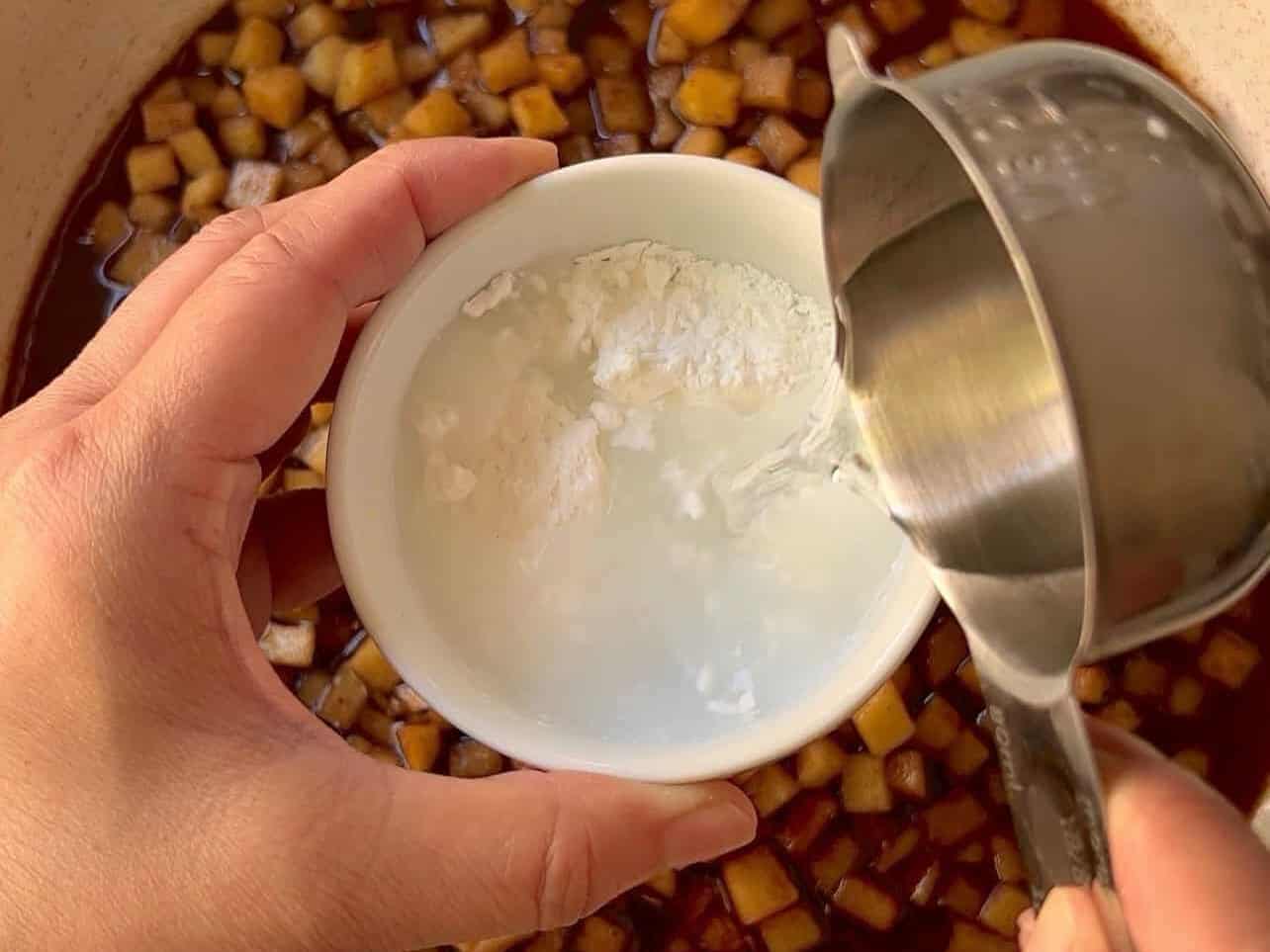 combining cornstarch and water in ramekin to create slurry for apple pie filling