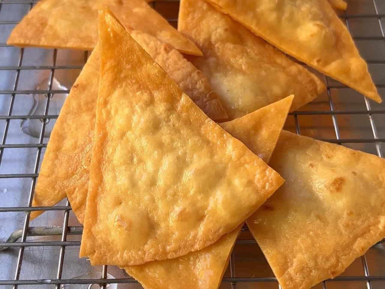 golden crispy fried tortilla chips draining on a wire rack