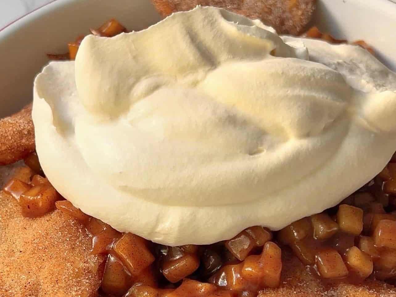 dollop of whipped cream on top a plate of apple pie nachos