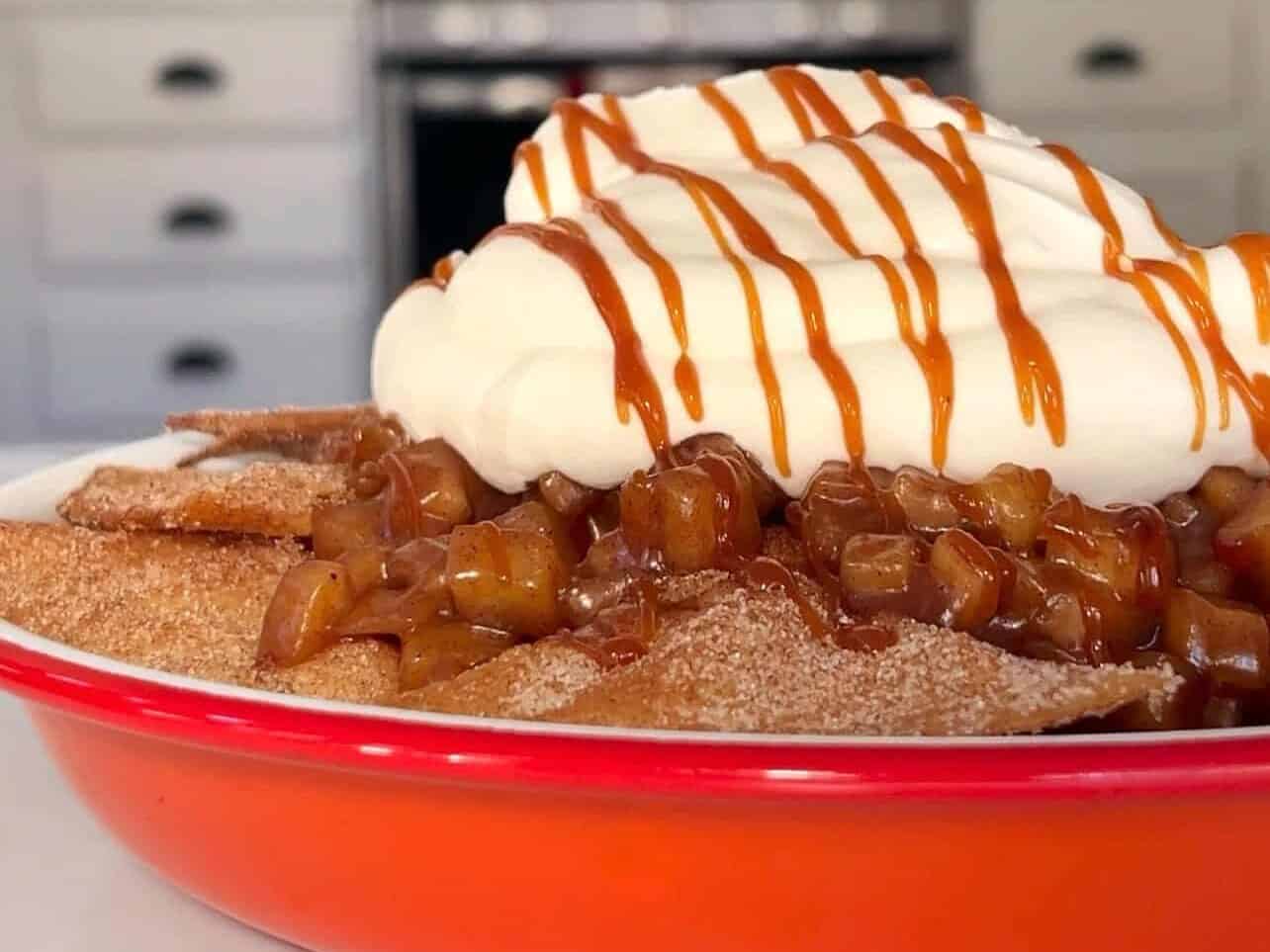 plate of apple pie nachos topped with whipped cream and caramel drizzle