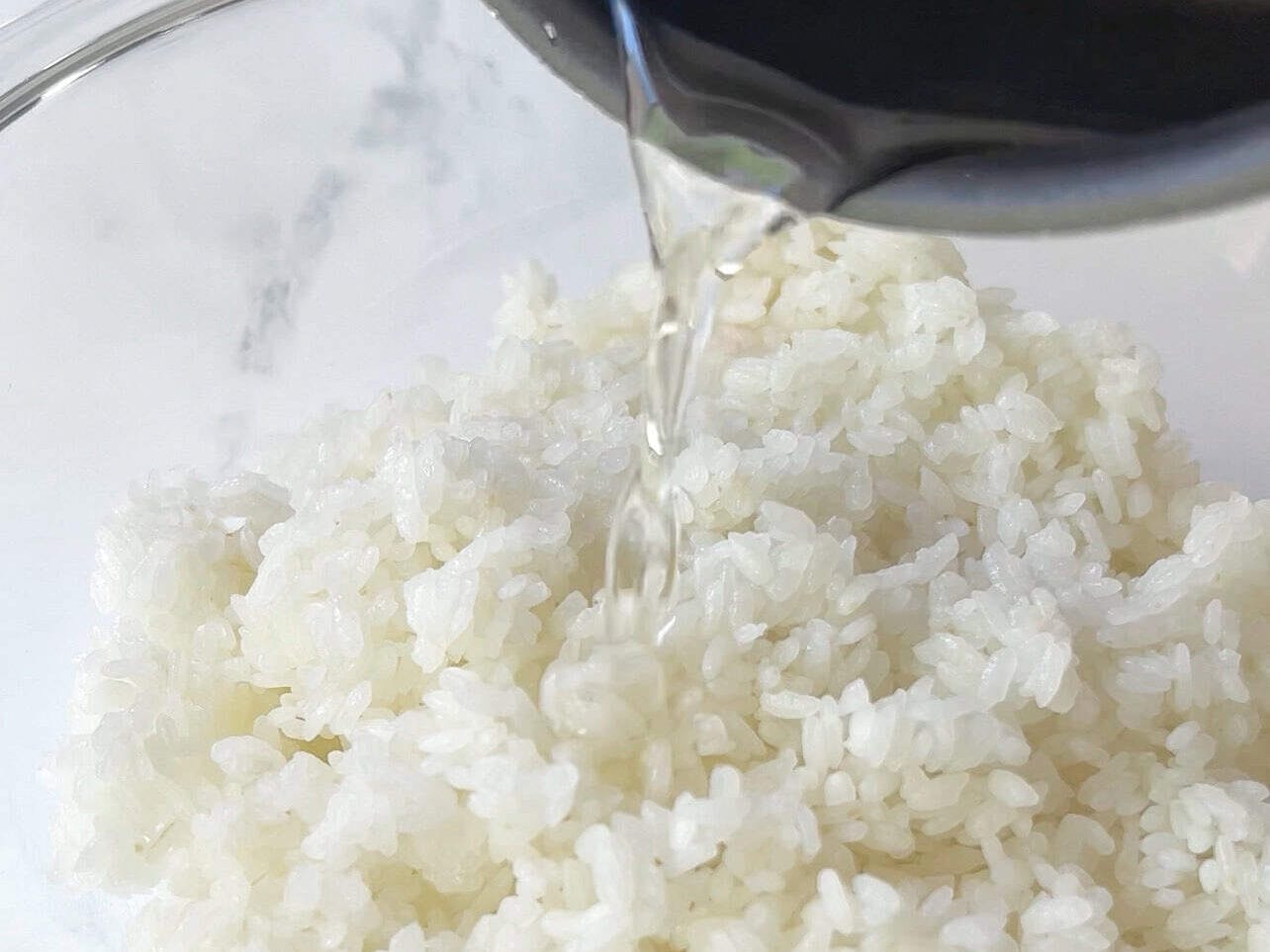 pour seasoned rice vinegar over hot rice to make sushi rice