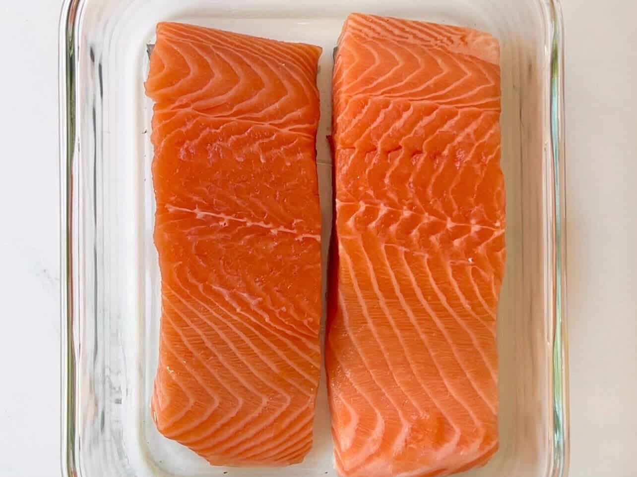 salmon fillets placed in Tupperware ready for marinade
