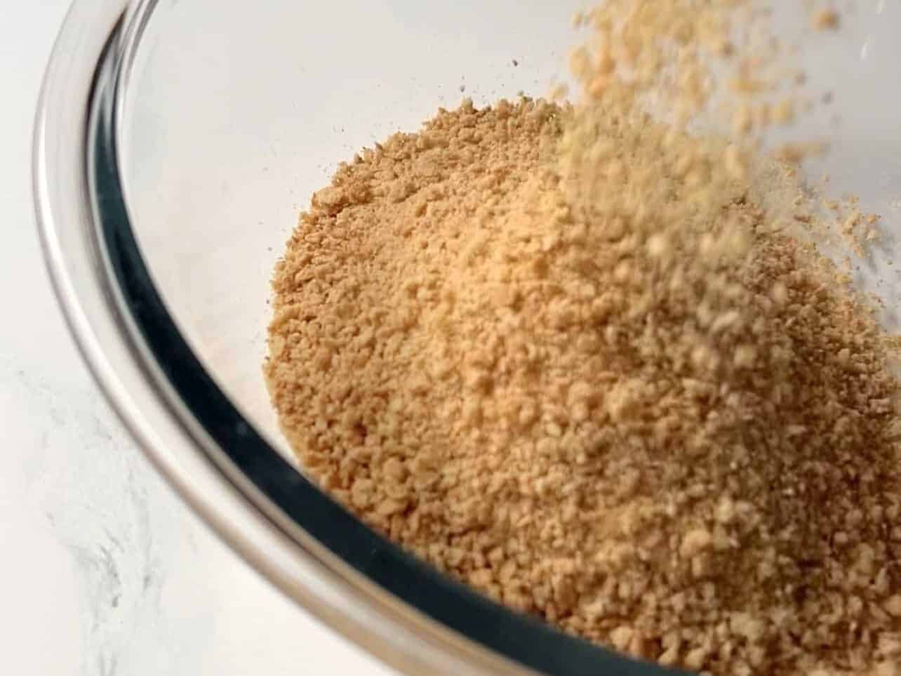 crushed graham crackers added to bowl to make cheesecake crust