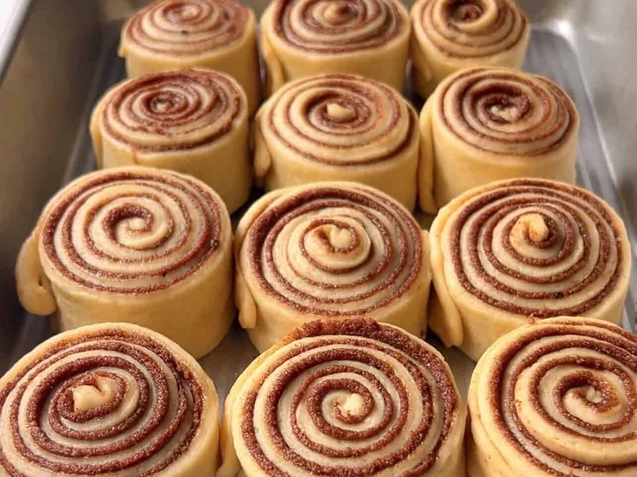 12 Cinnabon copycat cinnamon roll dough proofing in baking tray