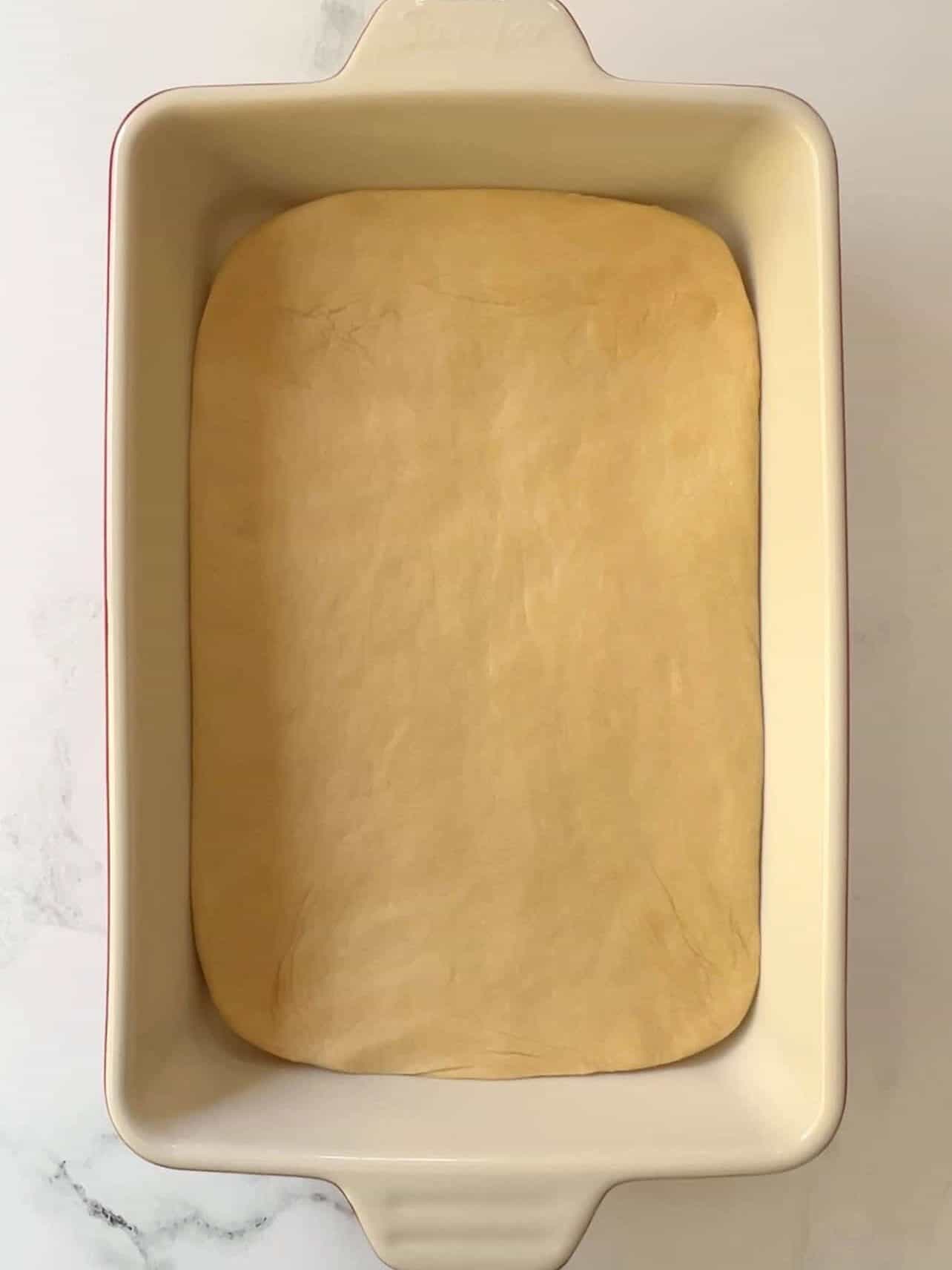 Cinnabon copycat cinnamon roll dough first rise in baking pan to encourage rectangle shape before rolling