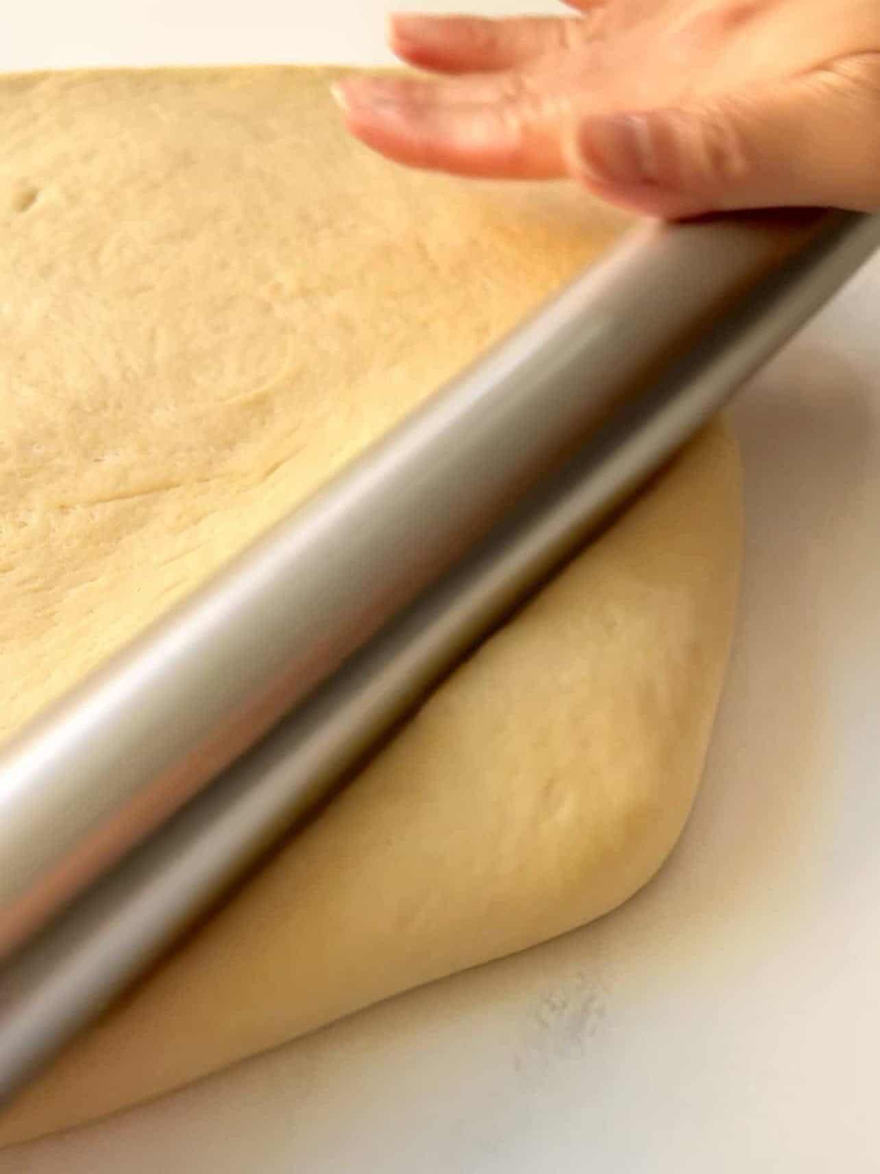 roll cinnamon roll dough corners evenly to achieve rectangle shape