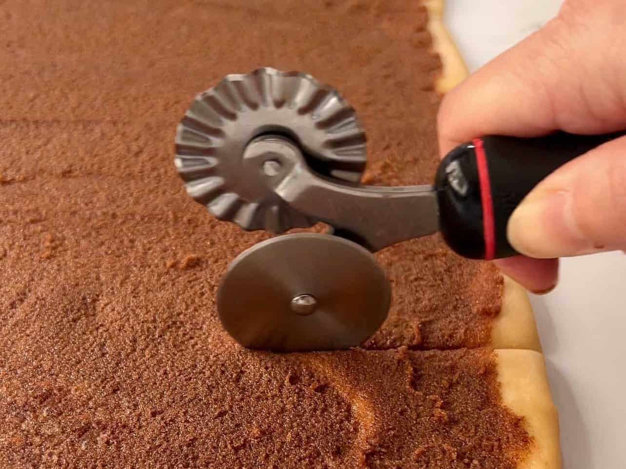 use of pasta wheel to cut cinnamon roll dough into strips